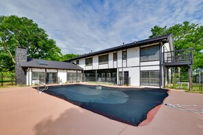 Un bâtiment moderne à deux étages, doté d’une piscine, de grandes fenêtres et d’un balcon.