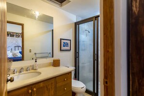 Une salle de bain avec un grand miroir, des meubles en bois, un lavabo et des toilettes.