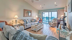 A spacious living room with a large sofa, a coffee table, and a dining area with chairs. - Topsail Beach Oceanfront Oasis w/ Stunning Views! (Sneads Ferry)