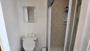 A bathroom with a toilet, a shower, and a mirror. - Moorfield Hotel (Blackpool)