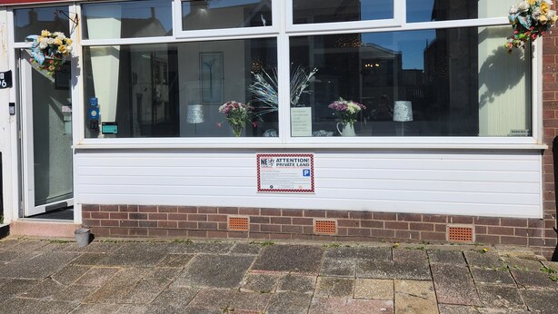 A storefront with a red awning labeled "MOORFIELD" and a contact number. There are flower arrangements on the windowsills, and a sign indicating private land. - Moorfield Hotel (Blackpool)