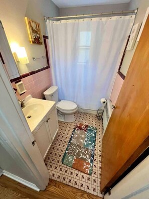 A small bathroom with a toilet, sink, and shower curtain.