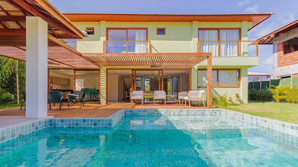 A two-story house with a swimming pool, outdoor seating, and a covered patio area.