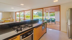 A modern kitchen with a large island, built-in oven, and a view of the outdoor patio area.