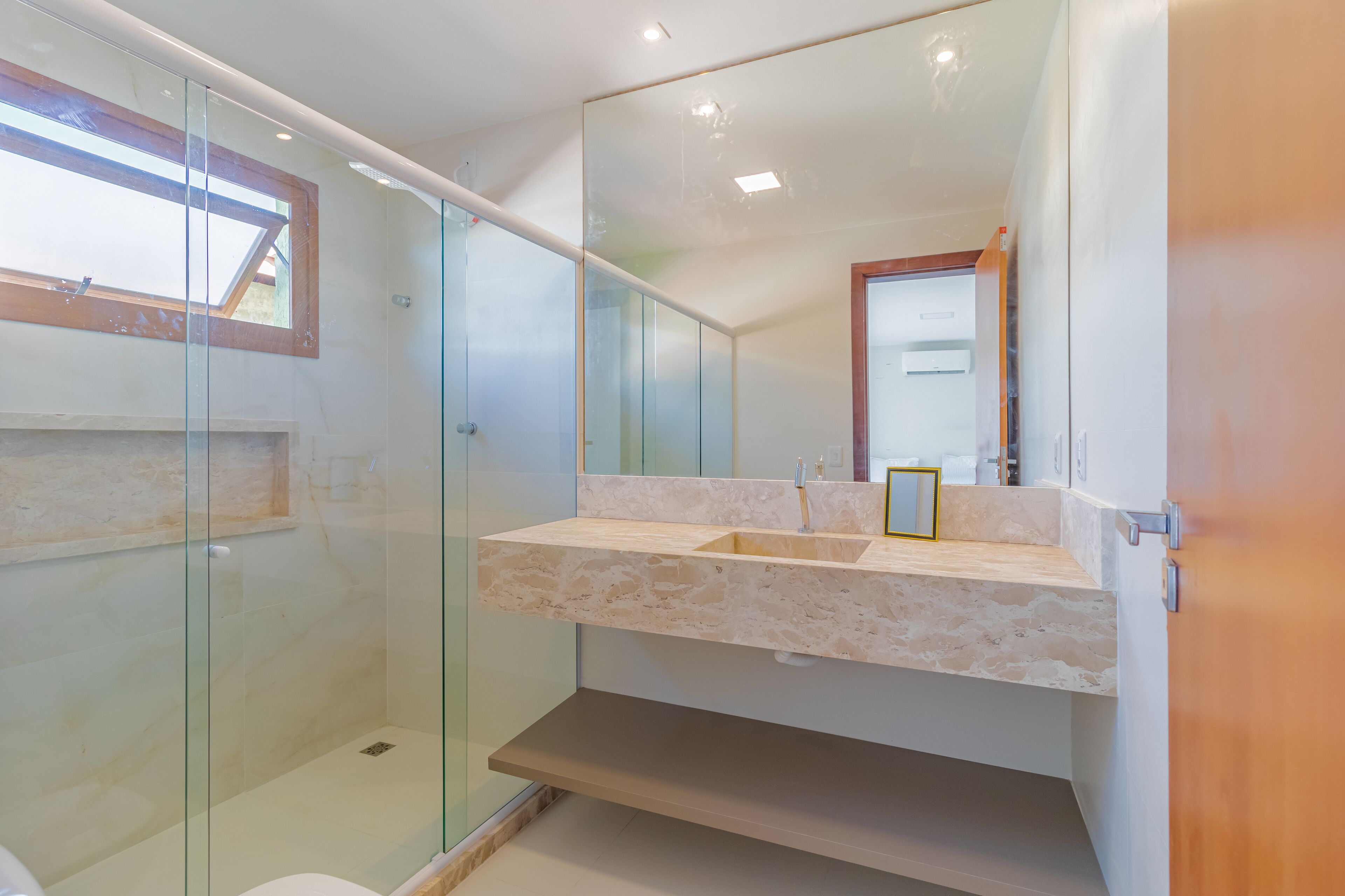 A modern bathroom with a glass-enclosed shower, a marble sink, and a large mirror.