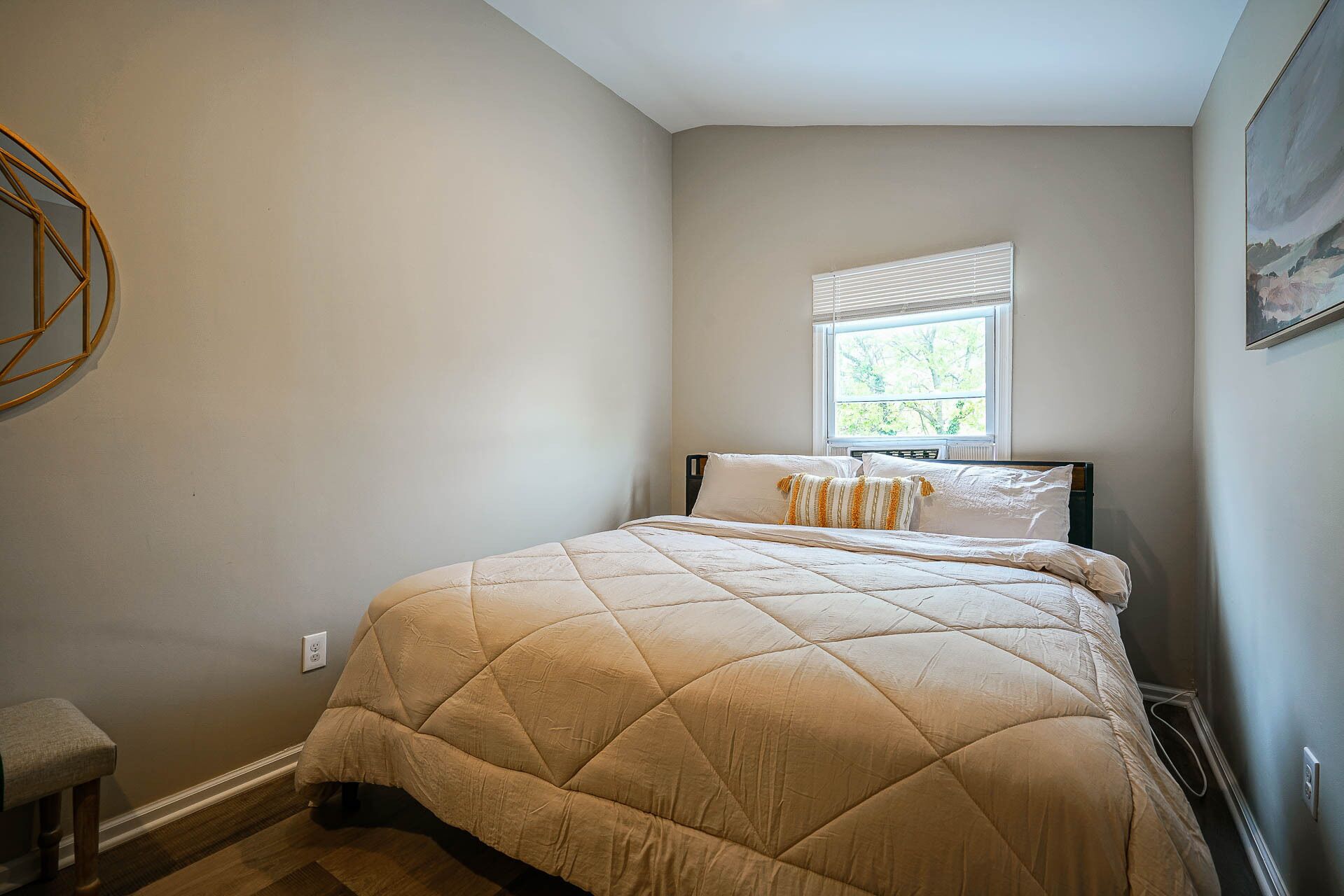 Une chambre à coucher avec un lit, une fenêtre et un tableau accroché au mur.