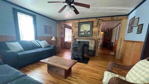 Ein Wohnzimmer mit einer Couch, einem Couchtisch, einem Kamin und einem Deckenventilator.