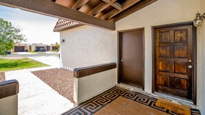 Un porche cubierto con una puerta de madera y un felpudo.
