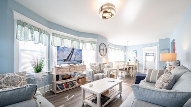 A living room with a television, sofas, a coffee table, and a dining area with chairs and a table. - Beach Block Ocean Views Steps from the Boardwalk (Ocean City)