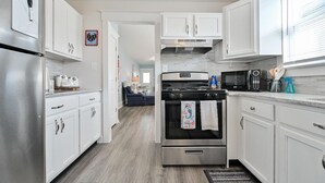 A modern kitchen with white cabinets, stainless steel appliances, and a central island. - Beach Block Ocean Views Steps from the Boardwalk (Ocean City)