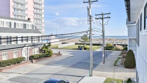 A residential street with a row of townhouses, a clear view of the ocean, and a utility pole in the foreground. - Beach Block Ocean Views Steps from the Boardwalk (Ocean City)