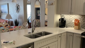 A modern kitchen with white cabinetry, stainless steel appliances, and a central island with a sink.