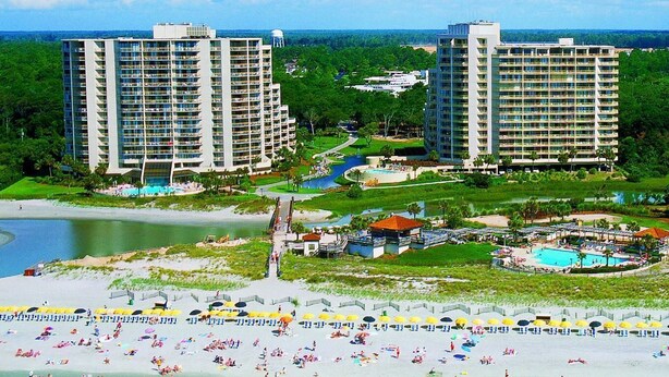 A resort with two high-rise buildings, a beach, and a pool area.