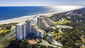 A coastal hotel with multiple high-rise buildings, a beachfront, and a landscaped area with a water feature.