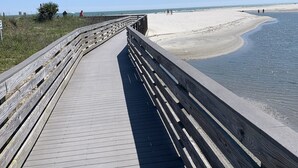 A wooden boardwalk leading to a sandy beach with clear skies.