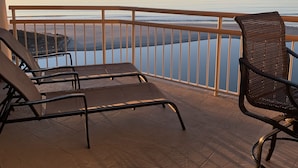 A balcony with two lounge chairs and a view of the ocean.