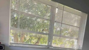 A room with a glass table, a blue trash bin, and a window with blinds. - Private suite, private entrance. (Deerfield Beach)