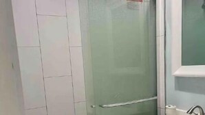 A bathroom with a glass-enclosed shower, a sink, and a mirror. - Private suite, private entrance. (Deerfield Beach)