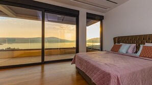 Una camera da letto con un letto grande, vista su un corpo d'acqua e un balcone con porte in vetro.