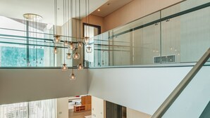 Ein modernes Interieur mit Treppe, Glasgeländer und einer Sitzecke mit kleinem Tisch und Stühlen.