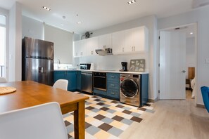 A modern kitchen with a wooden table, built-in appliances, and a checkered floor.
