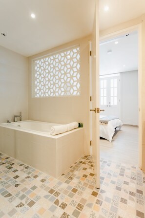 A modern bathroom with a freestanding bathtub, a decorative lattice partition, and a patterned floor.