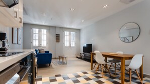 Una cocina moderna con horno integrado y cafetera, un comedor con mesa y sillas de madera, y un espejo grande en la pared.
