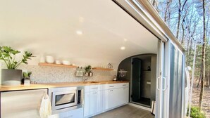 A modern kitchen with white cabinets, a wooden countertop, and a built-in oven. - Luxury, modern AIRSTREAM at June Farms! (West Sand Lake)