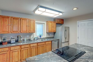 A kitchen with wooden cabinets, a stainless steel refrigerator, a dishwasher, and a black stove. - Lakefront Fairbanks Home w/ Private Beach! (Fairbanks)