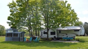 A recreational vehicle (RV) and a small cabin in a grassy area with trees. - Waterfront at the Pines of Canoe Neck (Abell)