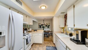 A modern kitchen with white appliances, a dining area, and a view of the living room.