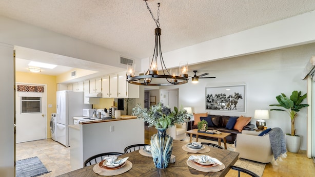 A spacious kitchen with white cabinets, a central island, and a dining area with a wooden table set for four.