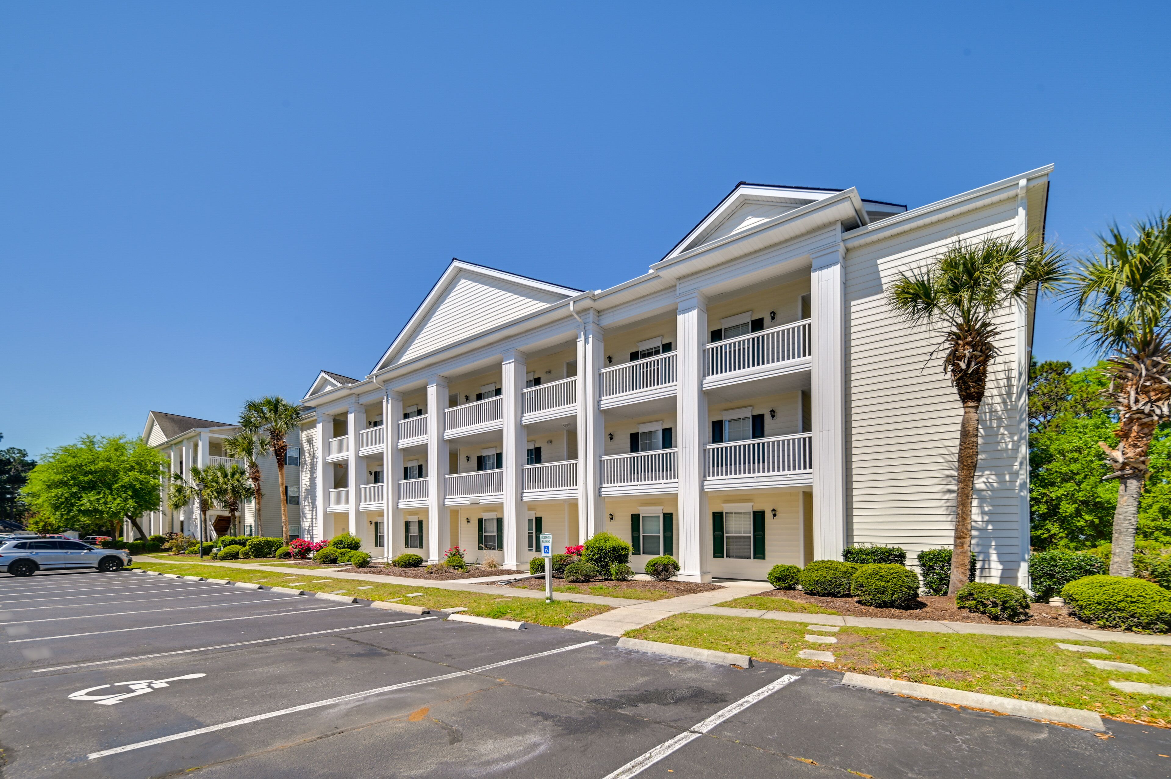 A multi-story hotel with a central courtyard, balconies, and a parking lot.