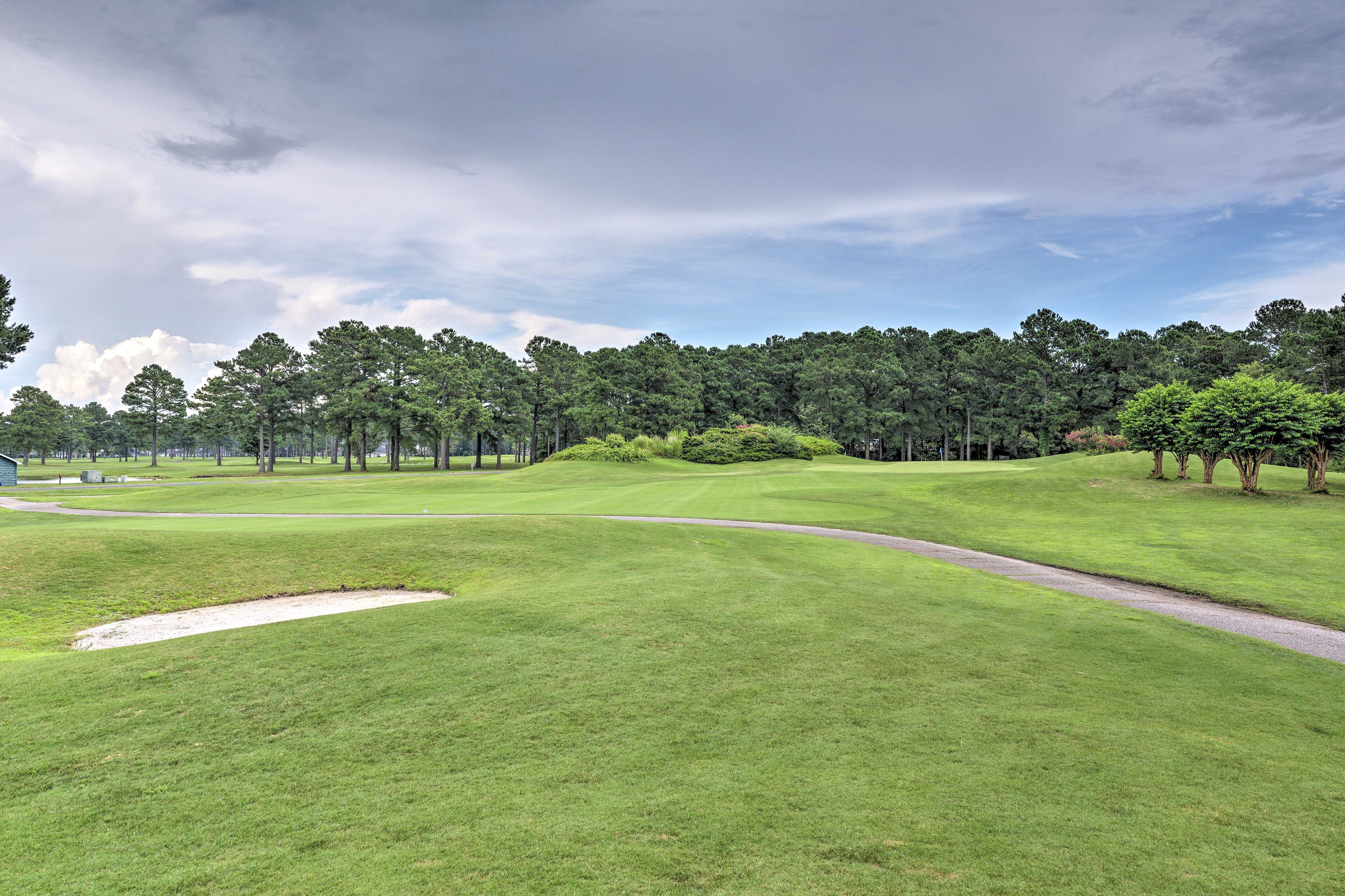 A golf course with a well-maintained green, sand bunkers, and a clear sky.