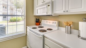 A kitchen with white cabinets, a stove, and a microwave. - Myrtle Beach Condo w/ Pool: Near Golf & Mall! (Myrtle Beach)