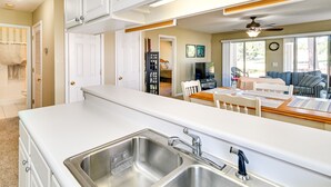 A kitchen with two stainless steel sinks, a wooden countertop, and a dining area with a table and chairs. - Myrtle Beach Condo w/ Pool: Near Golf & Mall! (Myrtle Beach)