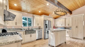 A spacious kitchen with wooden flooring, a stainless steel refrigerator, and a built-in oven.