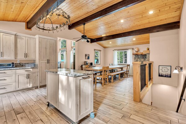 Une cuisine spacieuse dotée de meubles en bois, d’un grand îlot central et d’un coin repas avec une table et des chaises en bois.