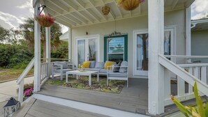 A covered porch with a white railing, a gray sofa with yellow cushions, and a green-framed window. - 3-acre Retreat, 3 Mi to Dtwn Jensen! Upscale Home (Jensen Beach)