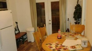 A compact kitchen with a refrigerator, a dining table with chairs, and a small window.