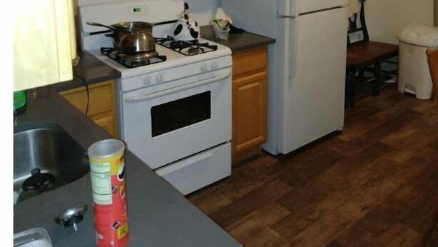 A compact kitchen with wooden cabinets, a white stove, a microwave, and a refrigerator.