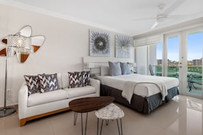 Un dormitorio moderno con cama, sofá, mesa de centro y balcón con vistas.