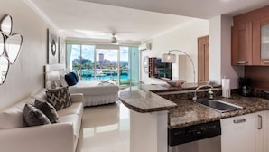 A modern apartment with a kitchen, dining area, and a balcony with a city view. - Sunrise Studio · Balcony · Water Backup (San Juan)