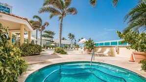 A swimming pool with a clear blue water, surrounded by palm trees and lounge chairs.