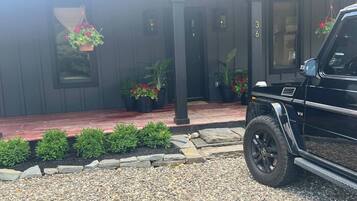 A black SUV parked in front of a house with a gravel driveway, a stone border, and potted plants.
