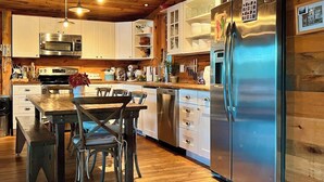 Una cocina moderna con armarios de madera, electrodomésticos de acero inoxidable y un comedor con mesa y sillas de madera.