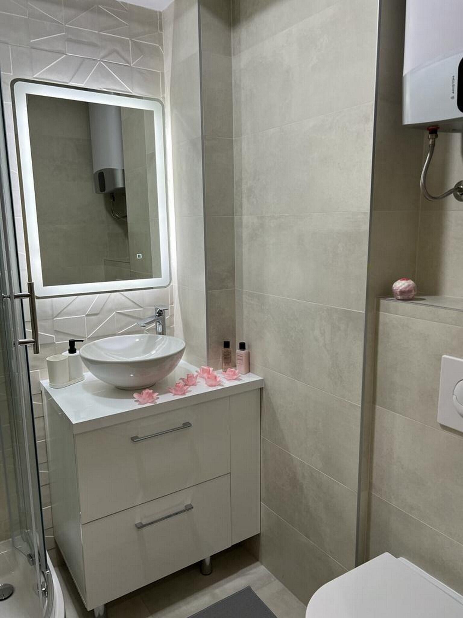 A modern bathroom with a large mirror, a white sink, and a shower area.