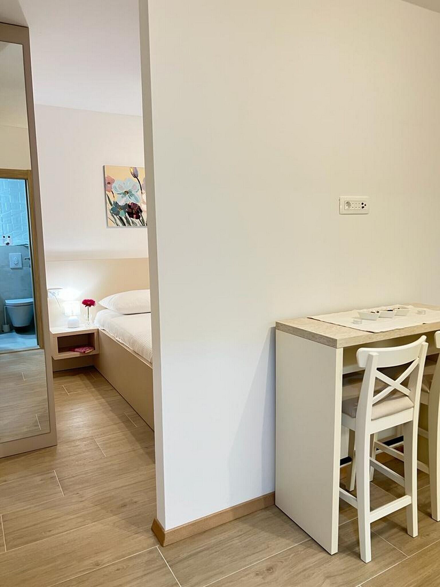 Un dormitorio pequeño y moderno con cama, mesita de noche y escritorio con silla.