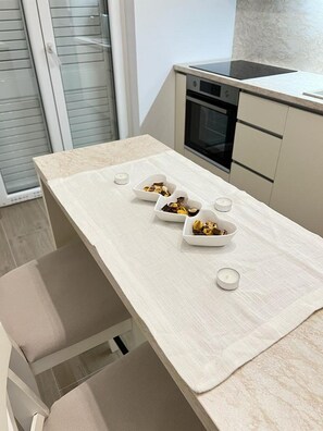 Eine moderne Küche mit heller Arbeitsplatte, einem eingebauten Backofen und einer Glastür zum Balkon.