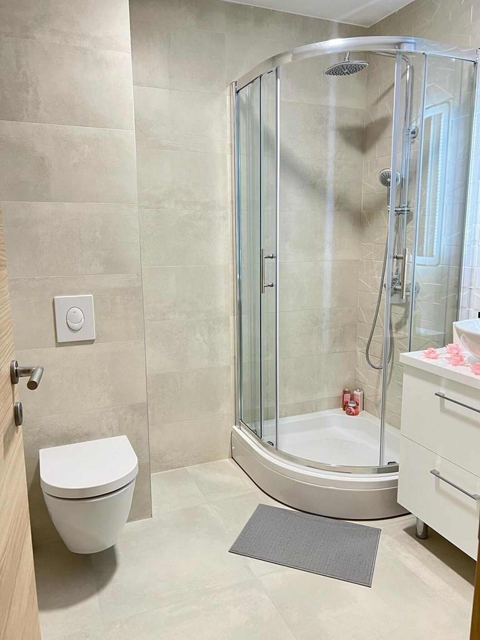 Un bagno moderno con doccia vetro, servizi igienici e mobile lavabo con specchio.